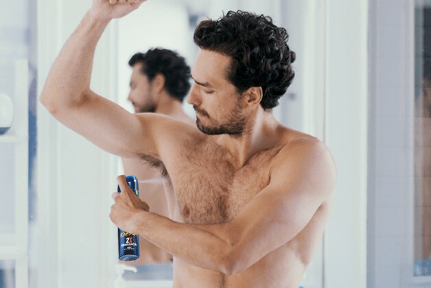 Hombre aplicando desodorante en su axila izquierda 