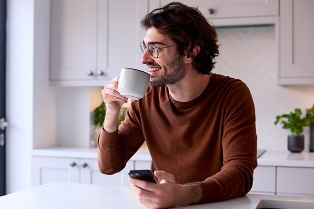 Hombre sonriendo mientras toma una taza de café